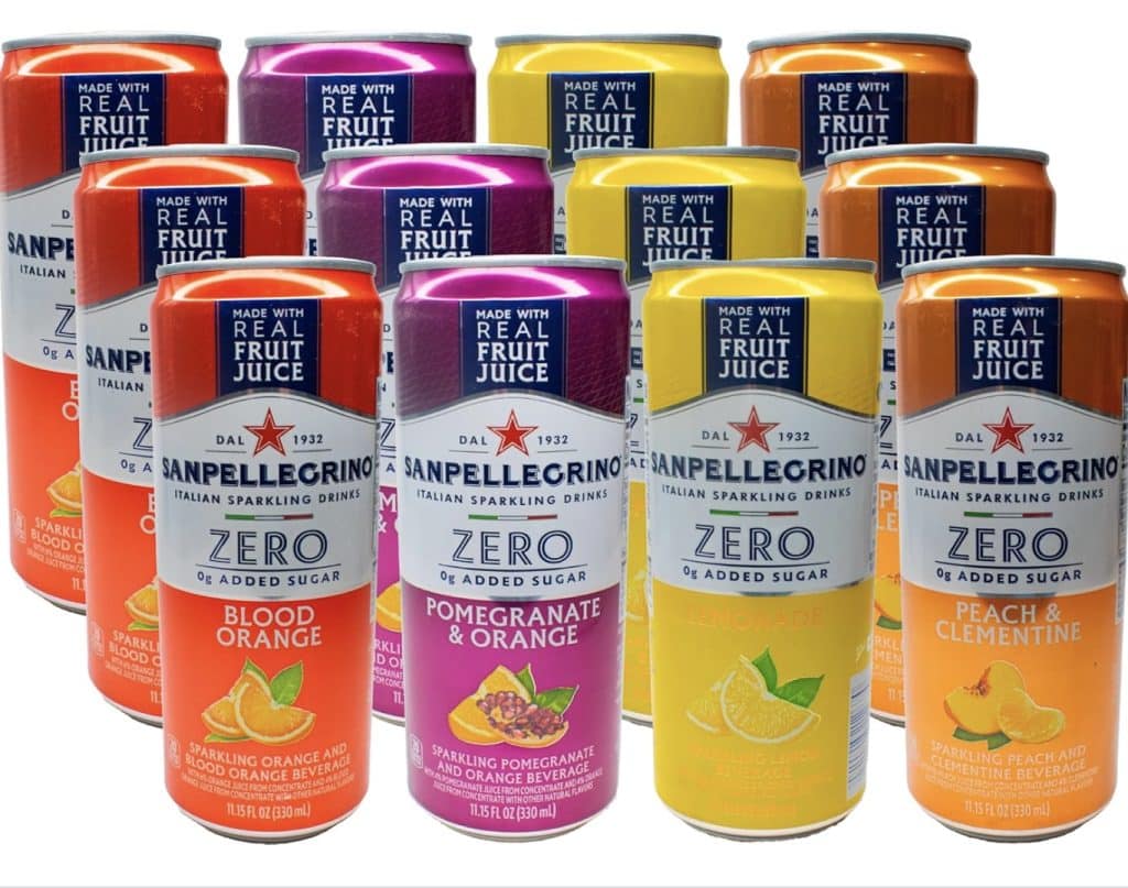 Cans of Sanpellegrino Zero sparkling drinks, reminiscent of a refined black cocktail drink, are displayed in three enticing flavors: Blood Orange, Pomegranate & Orange, and Lemon & Clementine. Each can proudly claims "Made with Real Fruit Juice" and "0% Added Sugar.